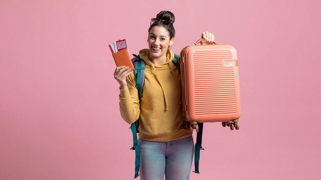 Donna felice che tiene il suoi bagaglio e biglietto aereo