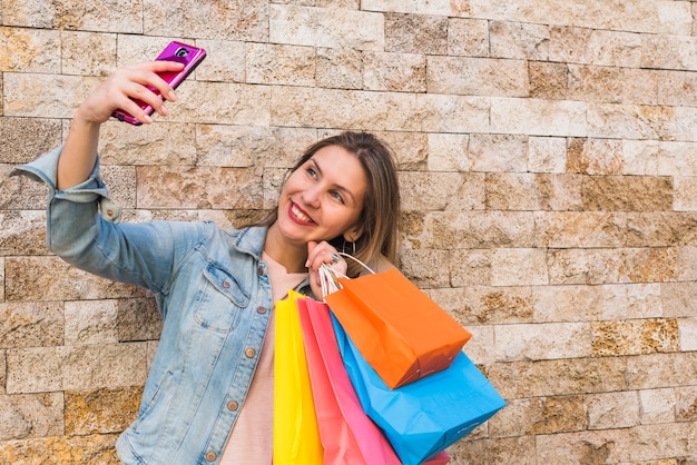 Donna felice con i sacchetti della spesa che prendono selfie