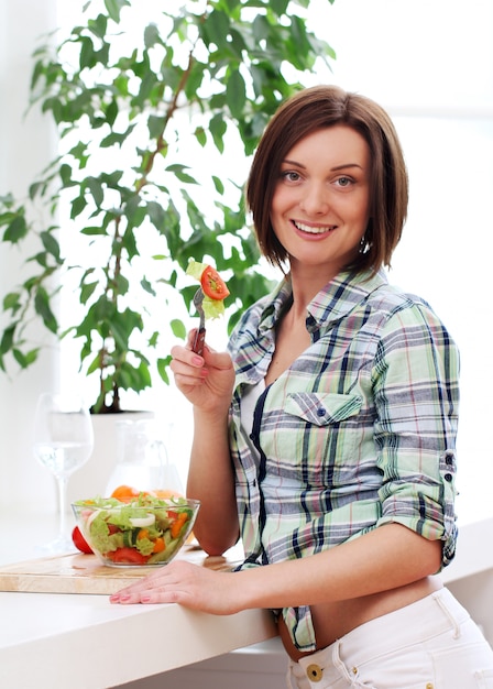 Donna felice con la ciotola di insalata fresca