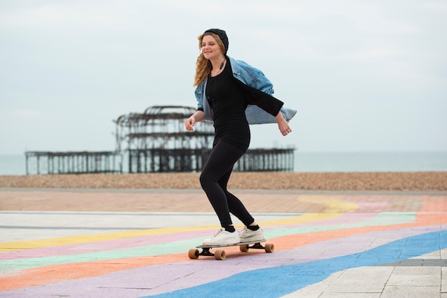 Donna felice del colpo pieno sullo skateboard