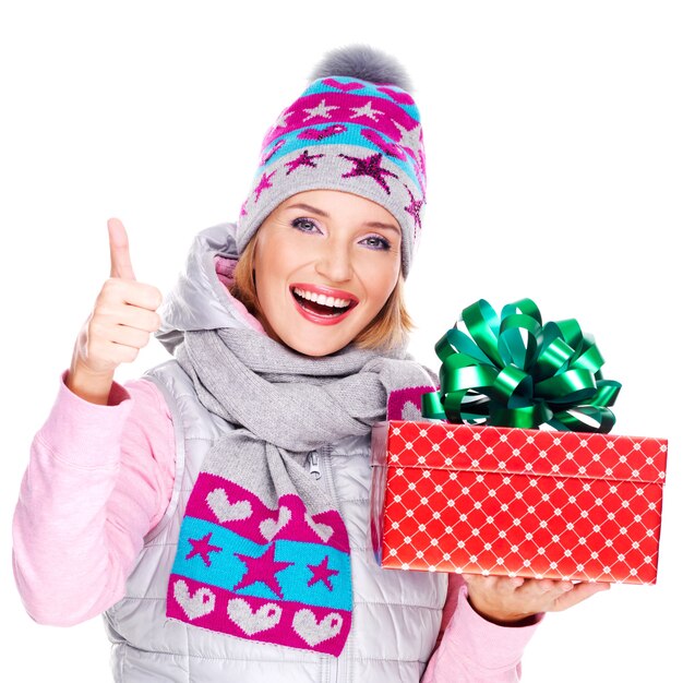 donna felice divertimento con un regalo in un capospalla invernale con il pollice in alto segno isolato su bianco