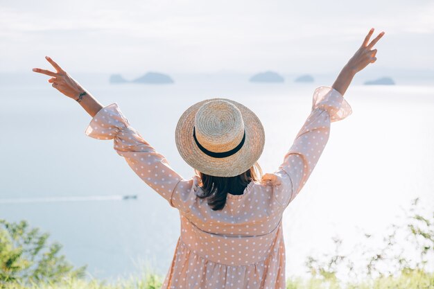 Donna felice in abito carino estivo e cappello di paglia in vacanza con viste esotiche tropicali