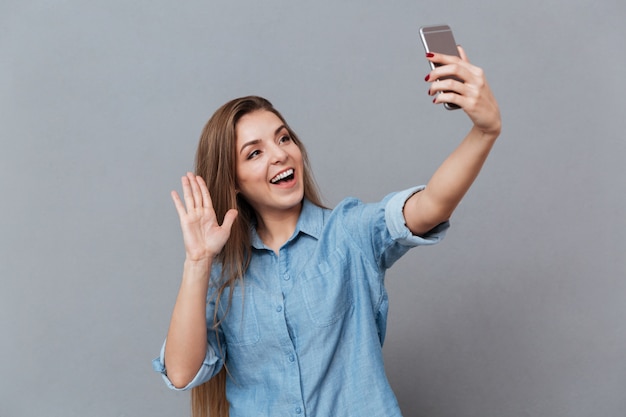 Donna felice in camicia che fa selfie sullo smartphone