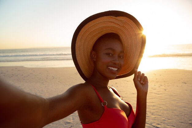 Donna felice in cappello che sta sulla spiaggia