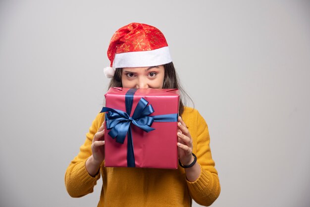 Donna felice in cappello della Santa che si nasconde dietro il contenitore di regalo.