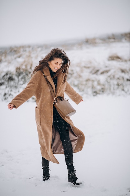 Donna felice in cappotto in inverno fuori nel parco