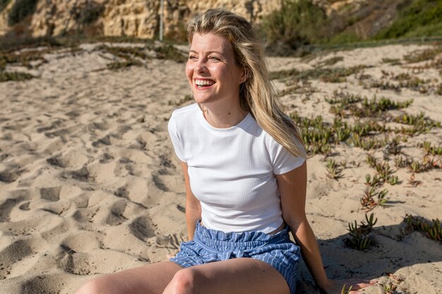 Donna felice in servizio fotografico spiaggia top bianco