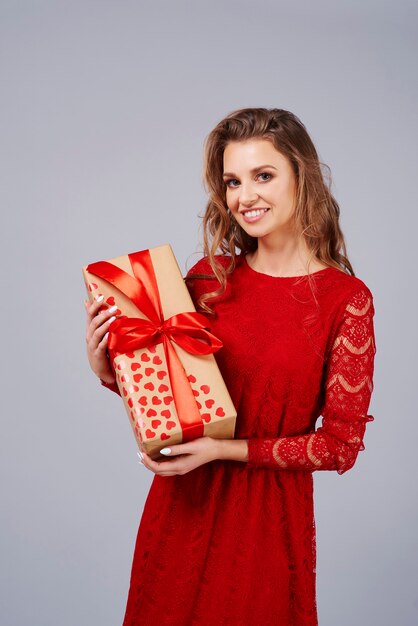 Donna felice in vestito rosso che tiene un regalo