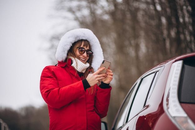 Donna felice parlando al telefono fuori in auto in inverno