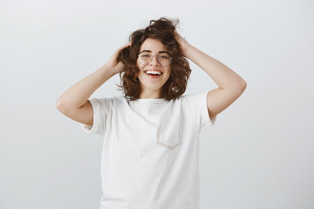 Donna felice spensierata con gli occhiali che tocca il suo nuovo taglio di capelli con la faccia soddisfatta