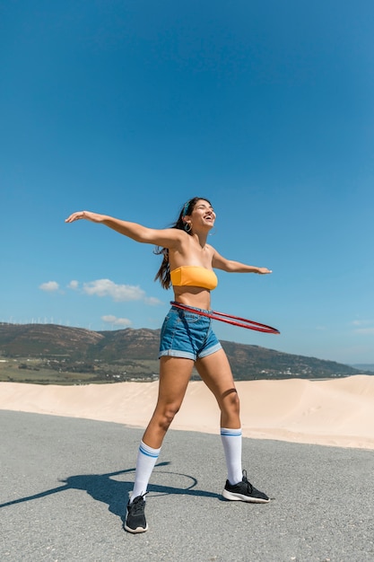 Donna felice sulla strada girando hula hoop