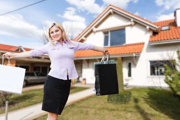 Donna felice sullo sfondo di una nuova casa. Ritratto di acquirente per la prima volta, proprietario di casa, affittuario di appartamento, inquilino o padrona di casa. Giorno del trasloco e acquisto del concetto di proprietà.