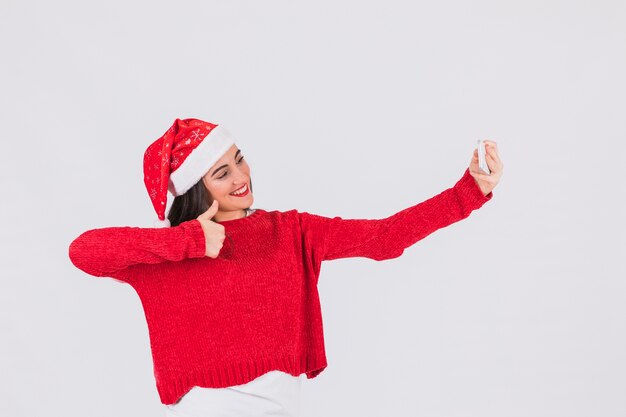 Donna festiva in cappello di Natale in posa per selfie