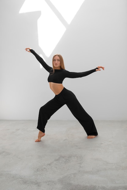 Donna flessibile che posa nel colpo pieno dello studio