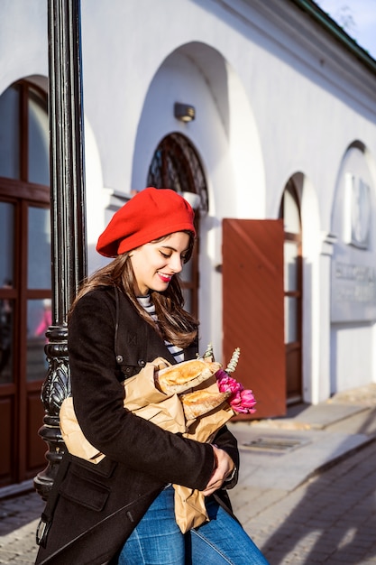 Donna francese con baguette sulla strada nel berretto