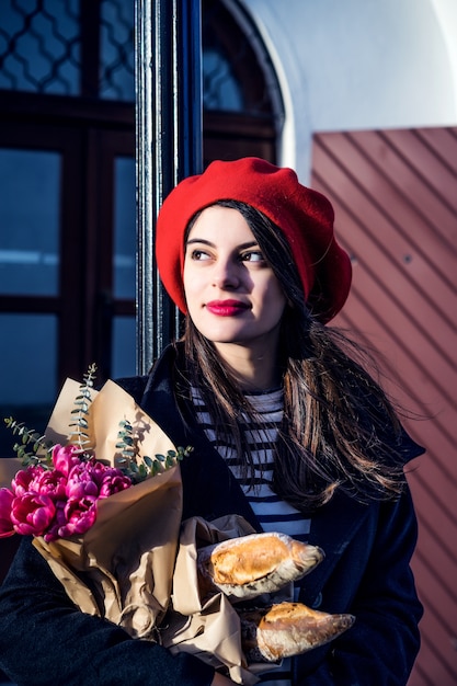 Donna francese con baguette sulla strada nel berretto