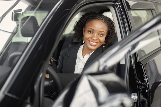 Donna giovane e allegra godendo di una nuova auto mentre è seduto all'interno Donna nera alla guida di un'auto Ragazza che indossa un costume nero