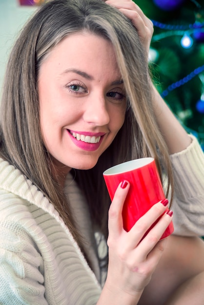 Donna, godendo, grande, tazza, appena, bollito, tè, caldo, lei, rilassante, divano, salotto. Caffè del mattino. La donna tiene una tazza di caffè rossa