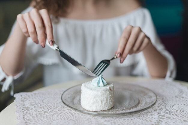 Donna godendo la torta rotonda bianca con forchetta e butterknife