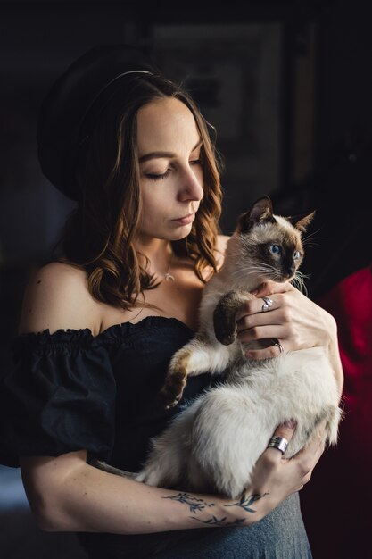 Donna graziosa che gioca con il gatto siamese