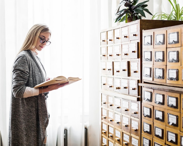 Donna graziosa che legge vicino alla finestra delle biblioteche