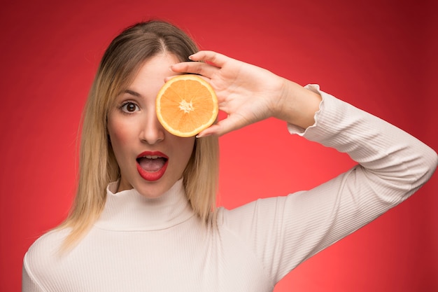 Donna graziosa che propone con la fetta arancione