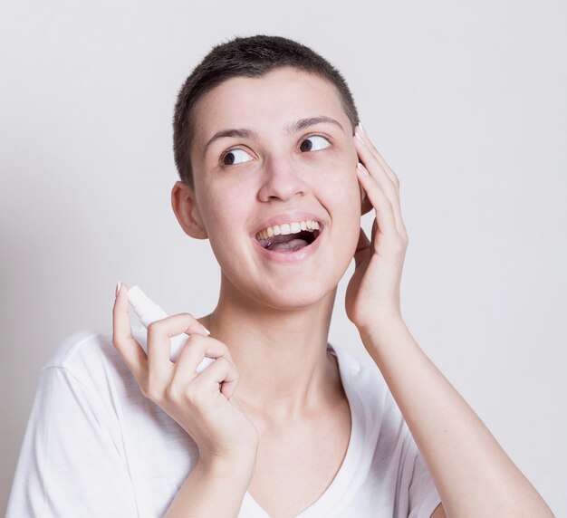 Donna graziosa che usando uno spray per il viso per la pulizia