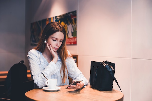 Donna graziosa che utilizza smartphone nel caffè