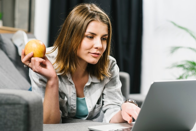 Donna graziosa con il computer portatile di lettura rapida della mela