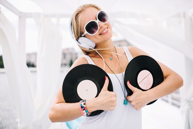 Donna graziosa con il vinile che mostra i pollici in su