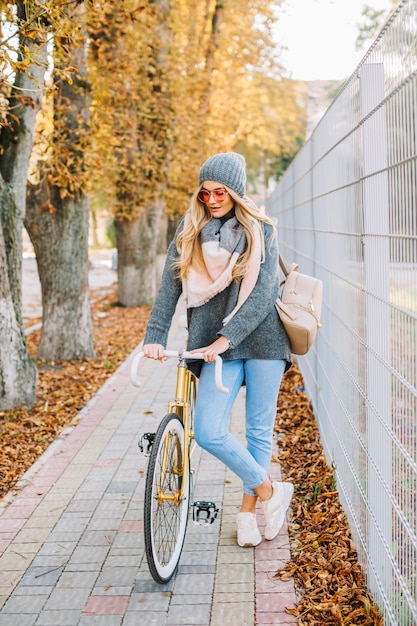 Donna graziosa con la bicicletta vicino al recinto