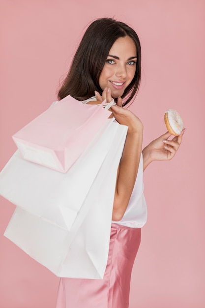 Donna graziosa con una ciambella su uno sfondo rosa