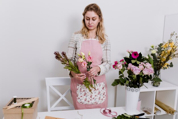 Donna graziosa del fiorista che prepara i fiori in negozio