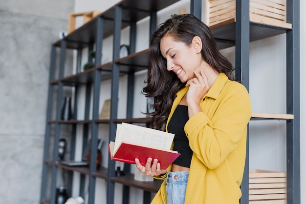 Donna graziosa di vista laterale che legge un libro