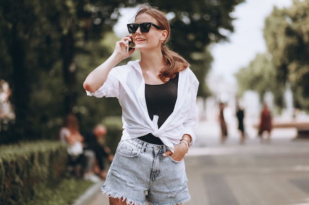 Donna graziosa fuori dalla strada usando il telefono