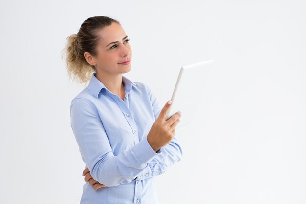 Donna graziosa pensierosa che utilizza computer tablet