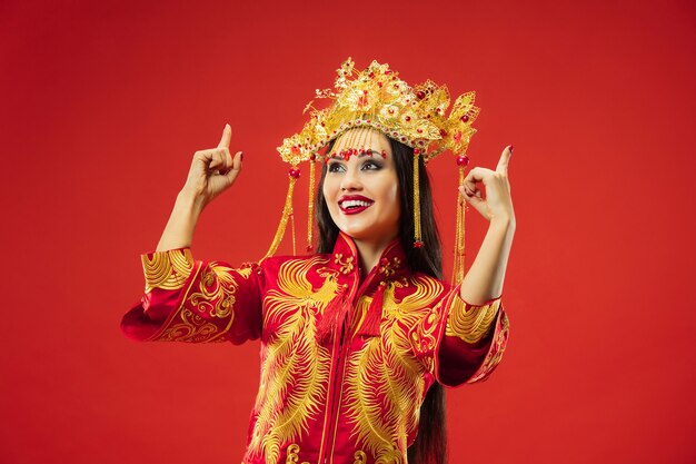 Donna graziosa tradizionale cinese allo studio sopra il rosso.