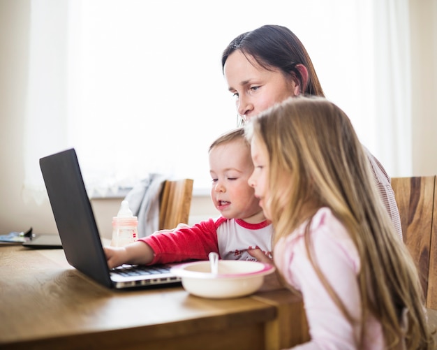 Donna guardando i suoi figli usando il portatile