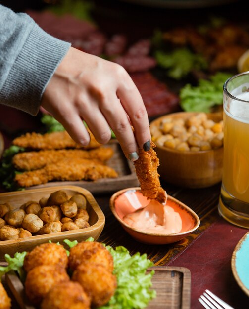 donna immergendo crocchetta di pollo in salsa nel setup di birra con le noci