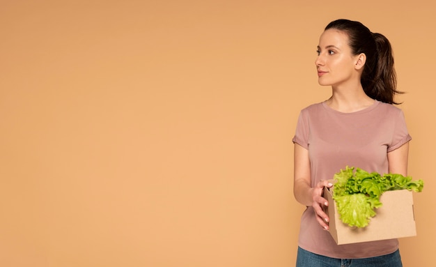 Donna in abiti casual che trasportano riutilizzabile scatola di cartone animato con verdure