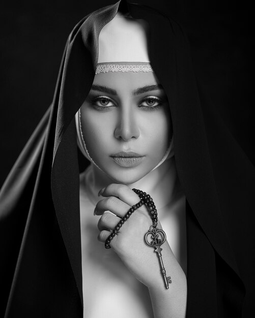 Donna in abiti di preghiera cristiana con una croce nello spazio buio
