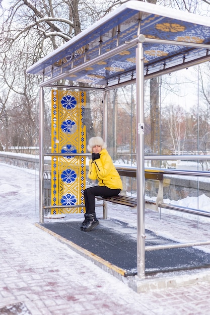 Donna in abiti invernali in una fredda giornata in attesa di un autobus a una fermata dell'autobus