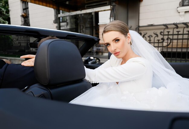 Donna in abito da sposa in posa in auto nera