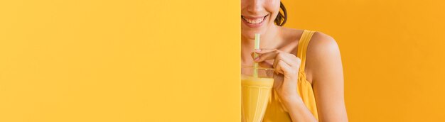 Donna in abito giallo con un bicchiere di succo