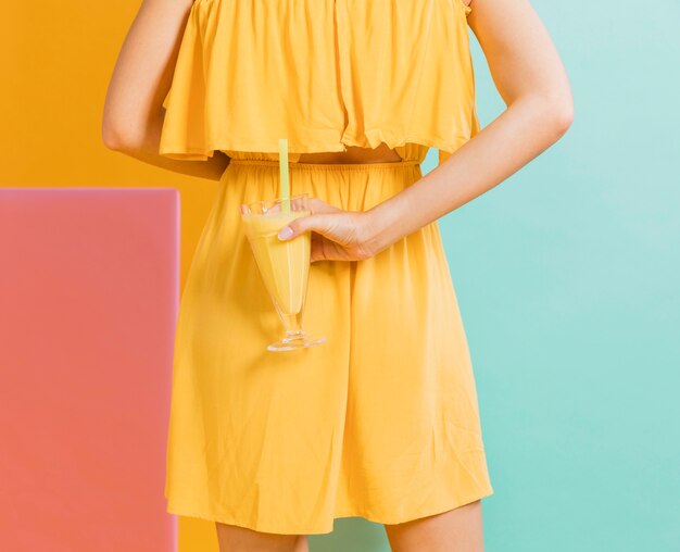 Donna in abito giallo con un bicchiere di succo