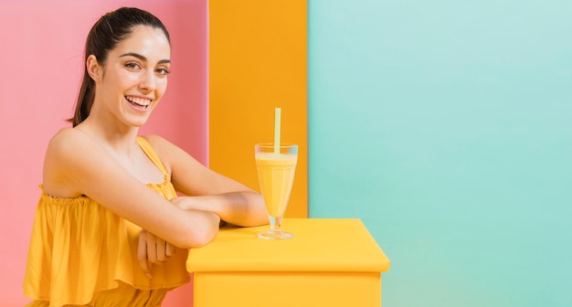 Donna in abito giallo con un bicchiere di succo