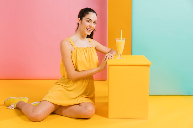 Donna in abito giallo con un bicchiere di succo