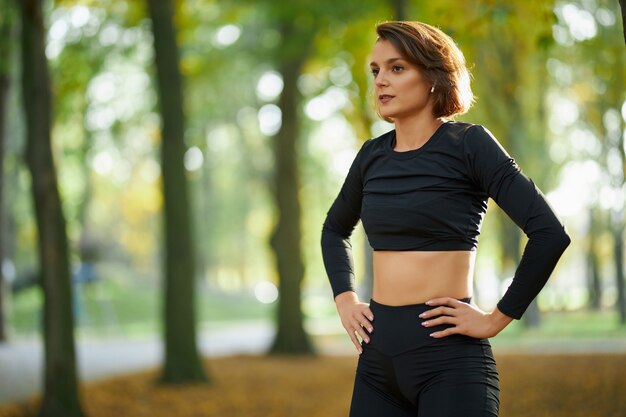 Donna in activewear rilassante tra esercizi al parco