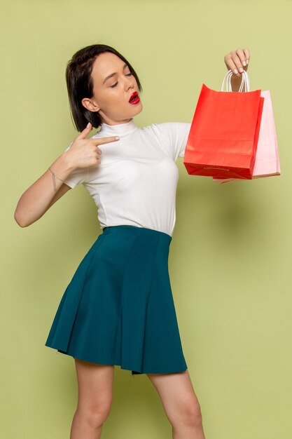 donna in camicetta bianca e gonna verde che tiene i pacchetti della spesa