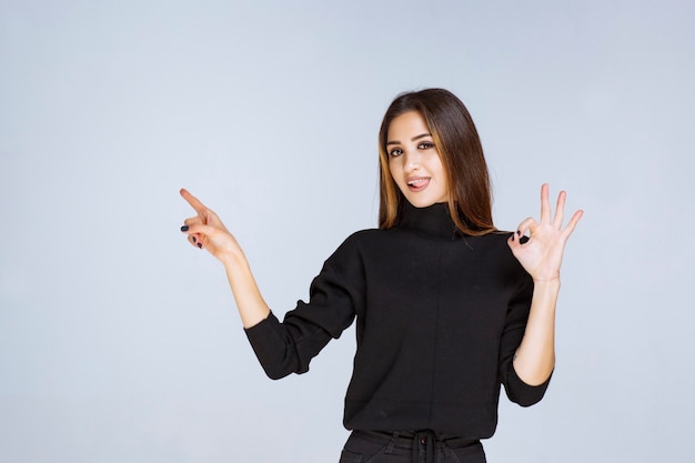 donna in camicia nera che mostra il segno positivo della mano.